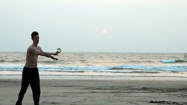 Неизвестный жонглирует стеклянным мячом на пляже — стоковое видео