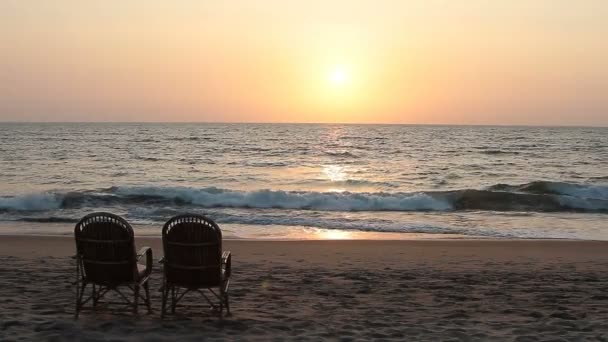Два стула возле береговой линии на закате — стоковое видео