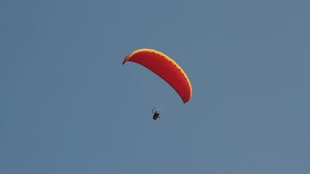 Parapente sobre as montanhas contra o céu azul claro — Vídeo de Stock