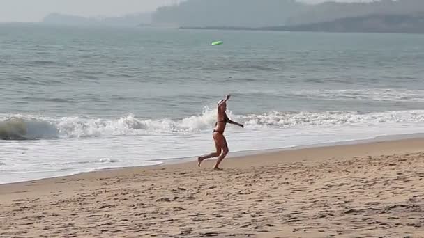 Красивая девушка играет Фрисби на пляже — стоковое видео