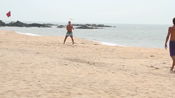 Homem não identificado jogando Frisbee na praia — Vídeo de Stock