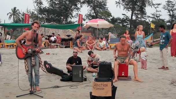 Oidentifierad man spelar musik på stranden. — Stockvideo