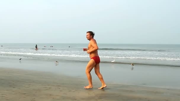 身份不明的男子在海滩上运行. — 图库视频影像