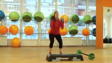 Dambıllarla egzersiz yapan genç bir kadın.