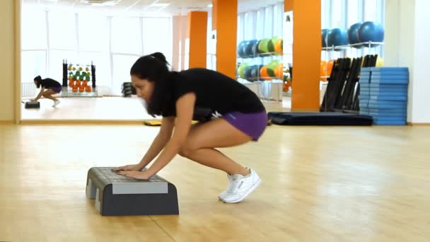 Femeia frumoasă pe tabla de pas în timpul exercițiilor fizice — Videoclip de stoc