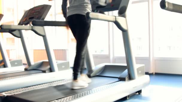 Pessoas no ginásio a exercitar-se. Corre numa máquina. Fora de foco — Vídeo de Stock
