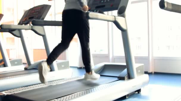 Gente en el gimnasio haciendo ejercicio. Ejecutar en una máquina. Fuera de foco — Vídeo de stock