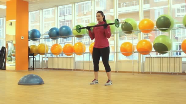 Молодая женщина делает упражнения с штангой — стоковое видео