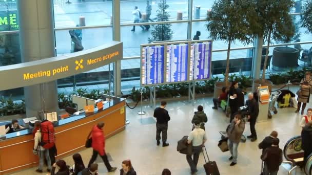 Emberek közelében belül Domogyedovói nemzetközi repülőtér érkezési csarnok információs tábla. — Stock videók