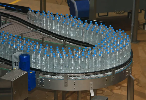 Plastic water bottles on conveyor and water bottling machine ind — Stock Photo, Image