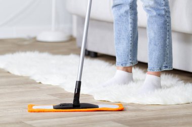 Ev hanımı yerleri paspasla temizler.