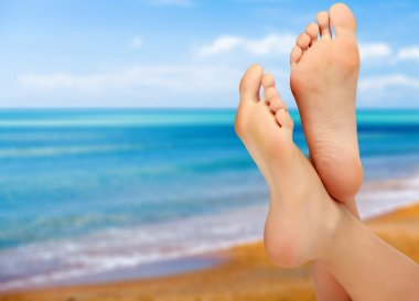 Female feet against blue sea and sky