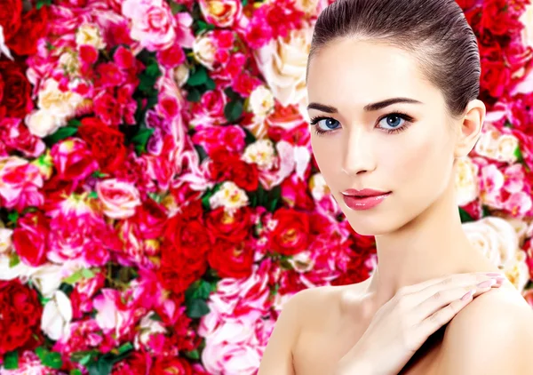 Hermosa mujer sobre un fondo floral con rosas rojas y blancas —  Fotos de Stock