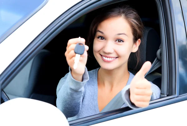 Chica feliz en un coche mostrando una llave y el pulgar hacia arriba gesto —  Fotos de Stock