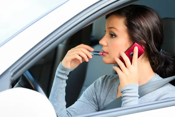 Conductora hablando por teléfono móvil y haciendo maquillaje . — Foto de Stock