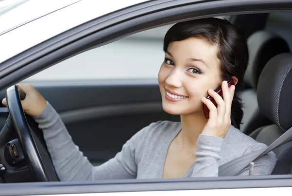 Happy young woman talk on cell phone sitting in white car — Stock Photo, Image