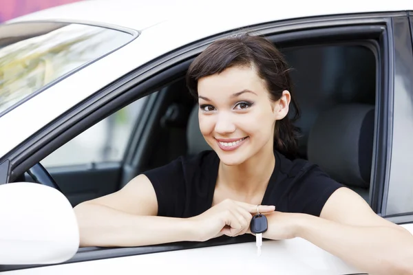 Chica bonita en un coche mostrando la llave — Foto de Stock