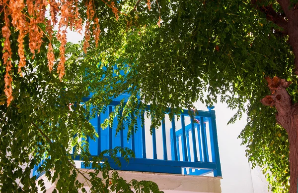 Classic balcony surrounded by green leaves of the tree of Mykono — Stock Photo, Image
