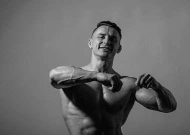 Spor tişörtsüz erkek model kaslarını esnetiyor.