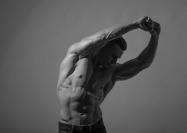 Spor tişörtsüz erkek model kaslarını esnetiyor.