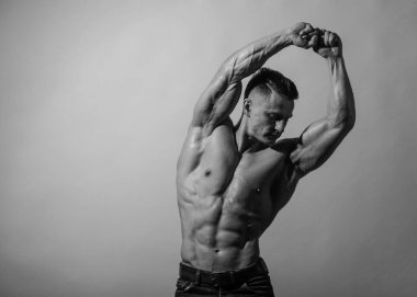 Spor tişörtsüz erkek model kaslarını esnetiyor.