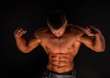 Spor tişörtsüz erkek model kaslarını esnetiyor.