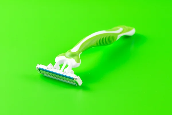 Green razor on green background — Stock Photo, Image