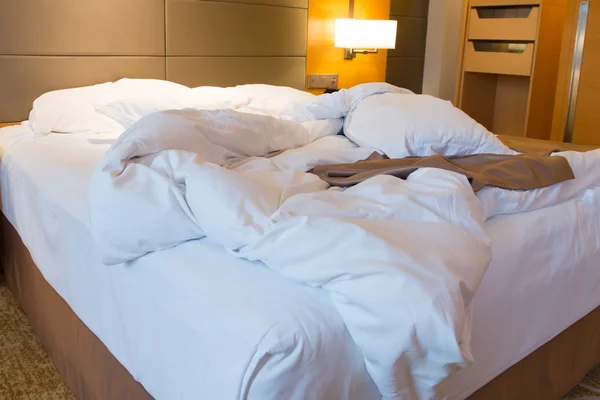 Onopgemaakte bed in hotel slaapkamer — Stockfoto