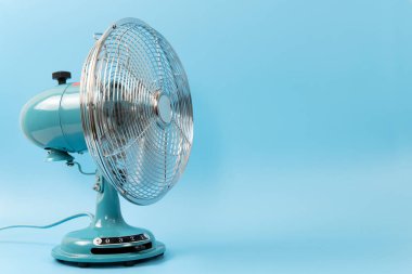 Klasik masa üstü vantilatörü mavi bir arkaplanda izole edildi
