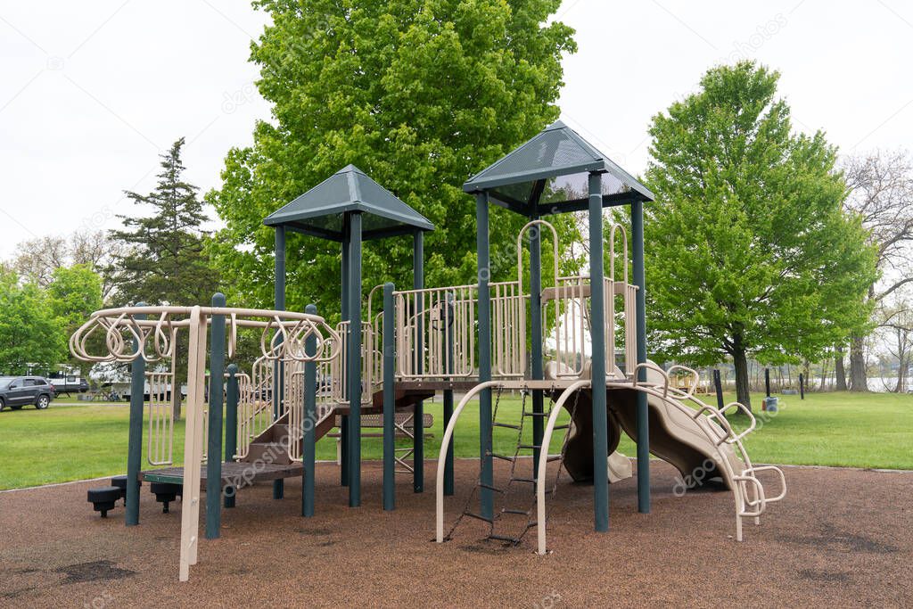 Children playground in public park surrounded by green trees