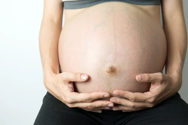 Barriga grávida com as mãos segurando — Fotografia de Stock