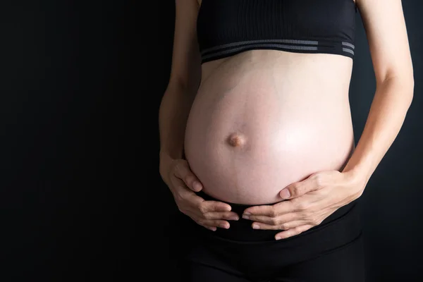 Pregnancy belly on dark background — Stock Photo, Image