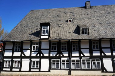 Goslar, Almanya - 21 Nisan 2016: Goslar, Almanya 'da eski bir ortaçağ yarı keresteli evi. Çatı doğal siyah kiremitlerle kaplı..                         
