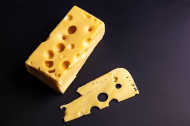 Siyah zemin üzerinde büyük delikleri olan Maasdam peyniri. 