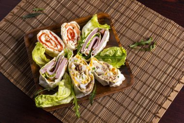 Somon, ton balığı, jambon, yumurta ve yeşil sebzelerle dilimlenmiş yumurta ruloları bambu hasırında. Üst görünüm.