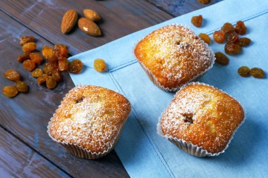 Tahta masadaki mavi peçeteye krema şekerli mini kekler. Seçici odak. 