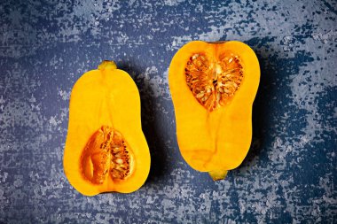 İki yarımlık taze, olgun balkabağı sıralaması grunge blue background üzerinde tereyağlı kabak.