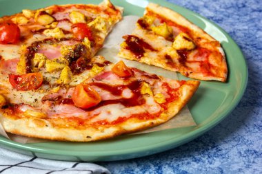 Pizza baked with bacon chicken mozzarella and cherry tomatoes. 