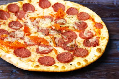 Biberli pizza, salamlı mozzarella ve ahşap masadaki domatesler. Seçici odak.