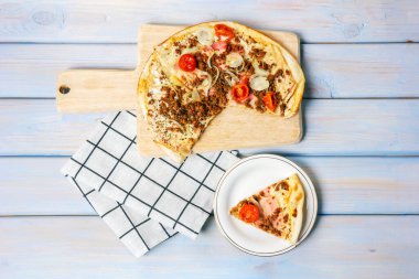 Pastırmalı pizza, dana eti, soğan, kiraz domatesleri ve ahşap masada mozzarella. Üst görünüm.