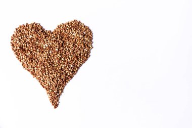 Beyaz arka planda kalp şeklinde karabuğday taneleri. Yemek malzemesi. Üst görünüm.