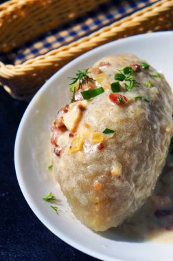 Sos soslu Cepelinai Zeppelin, çıtırtılar ve yeşillikler - dereotu ve yeşil soğan. Geleneksel Litvanya yemekleri. Seçici odak.                            