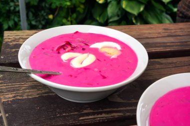 Soğuk pancar çorbası, yumurta ve ekşi krema, dışarıda, ahşap masada. Seçici odak.                                         