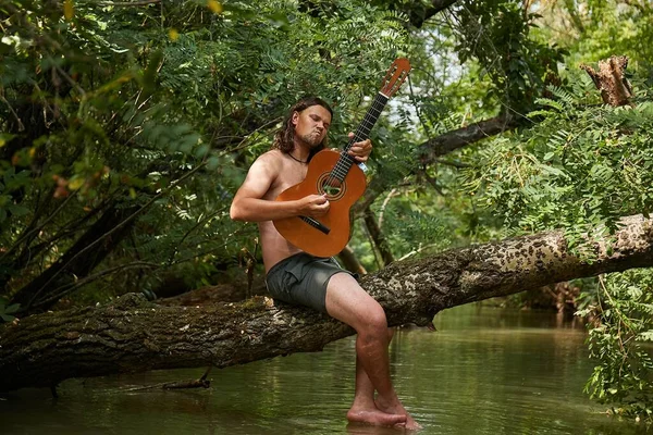 Playing the guitar on a tree above a river