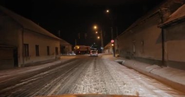 Geceleri bir köyde karda araba sürmek.