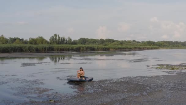 Gitarrespielen auf einer Matratze auf dem Wasser — Stockvideo