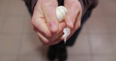 Elinde bir parça sarımsak, soyulmuş.