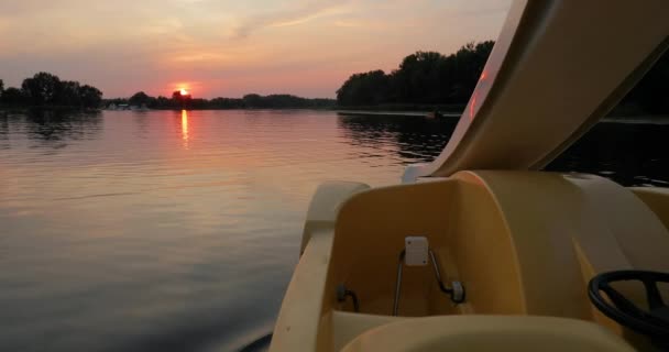 Paseo al atardecer en un lago en un bote a pedal — Vídeo de stock