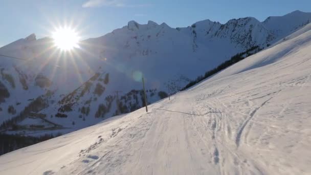 Skidåkning ner för en sluttning solljus flammande från nedgående sol — Stockvideo