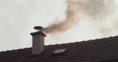 Kırsal evdeki çatı bacasından duman, yanan odun ve kömürden çıkan yoğun duman. Kötü ısıtmadan dolayı hava kirliliği. 4K 60 fps yüksek çerçeveli görüntü